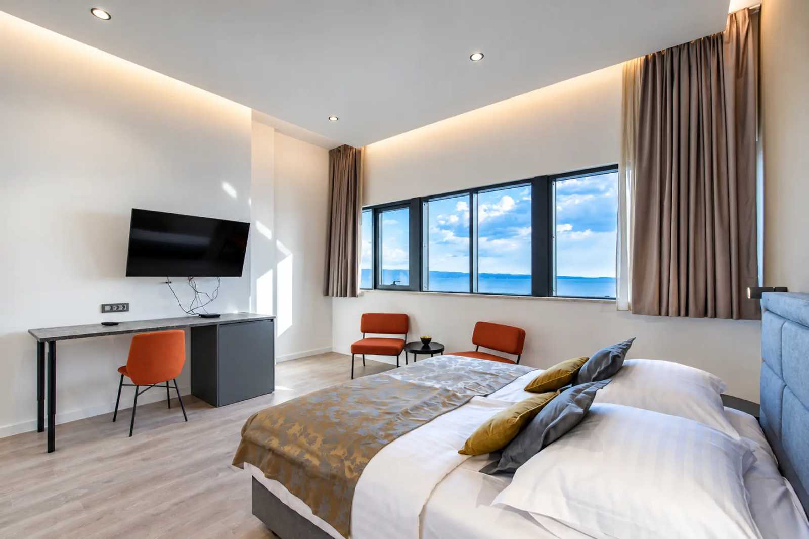 Guest room with desk, television and sea-view windows